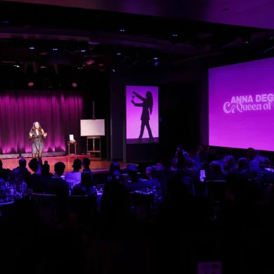 Wide view of a full theater audience watching Anna DeGuzman perform
